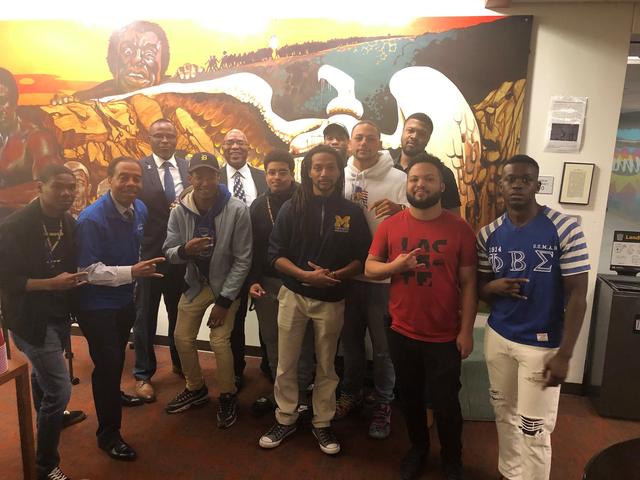 Fraternity gathering in front of a mural